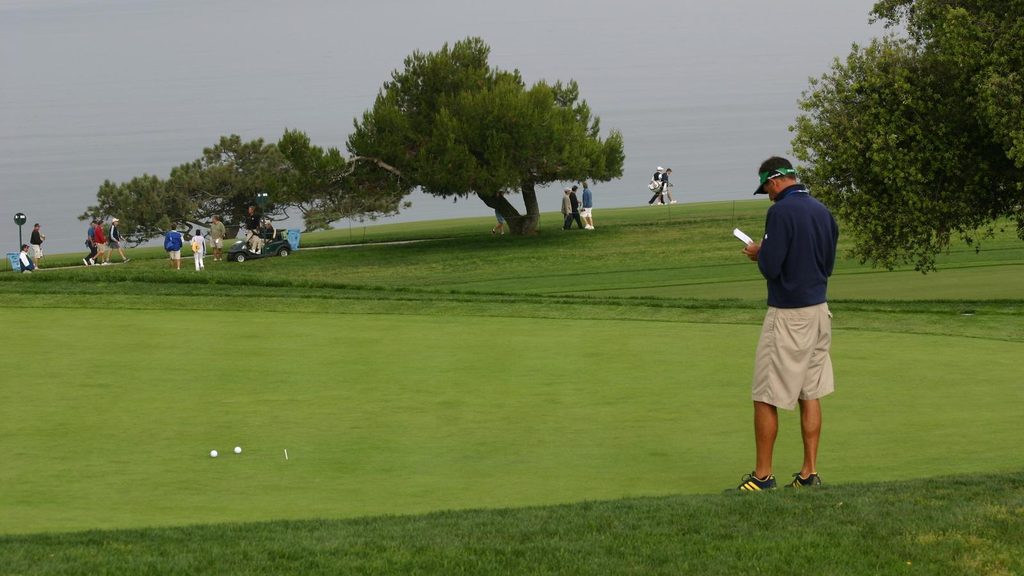 A golf caddie charting hole locations